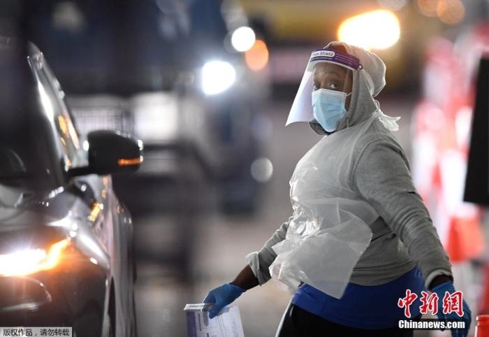 當(dāng)?shù)貢r(shí)間12月18日，英國(guó)政府公布的數(shù)據(jù)顯示，當(dāng)天英國(guó)新增奧密克戎毒株感染病例10059例。鑒于奧密克戎毒株感染病例激增，住院人數(shù)不斷上升，倫敦市長(zhǎng)宣布倫敦進(jìn)入“重大事故”狀態(tài)。圖為倫敦的一個(gè)免下車檢測(cè)中心，一名醫(yī)務(wù)工作者正準(zhǔn)備對(duì)司機(jī)進(jìn)行核酸檢測(cè)。