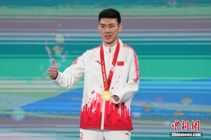 3月6日，梁景怡在延慶頒獎(jiǎng)廣場(chǎng)領(lǐng)獎(jiǎng)臺(tái)上豎起大拇指。當(dāng)日，在國(guó)家高山滑雪中心舉行的北京2022年冬殘奧會(huì)殘奧高山滑雪男子超級(jí)大回轉(zhuǎn)—站姿決賽中，中國(guó)選手梁景怡奪得冠軍。 <a target='_blank' href='/'>中新社</a>記者 楊華峰 攝