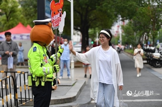 6月7日上午9時(shí)，隨著鈴聲的響起，2023年江西高考正式開(kāi)考，江西省的53.57萬(wàn)考生以縣（區(qū)）為單位隨機(jī)安排在全省256個(gè)考點(diǎn)、18968個(gè)考場(chǎng)參加高考。圖為“小熊交警”和考生擊掌鼓勵(lì)。 人民網(wǎng)記者 時(shí)雨攝