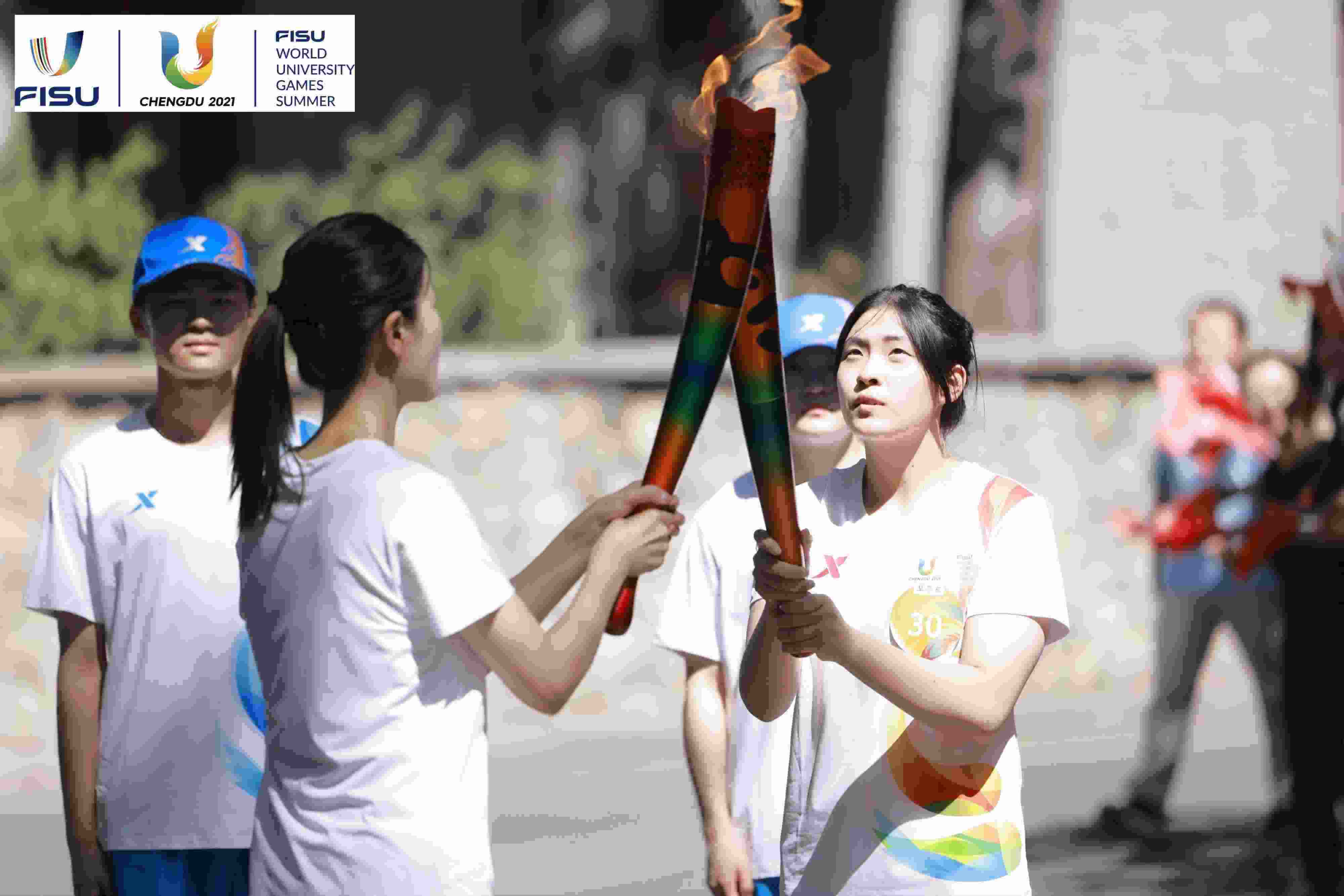 兩名大運(yùn)會火炬手進(jìn)行火炬?zhèn)鬟f。 圖片來源：成都大運(yùn)會執(zhí)委會供圖