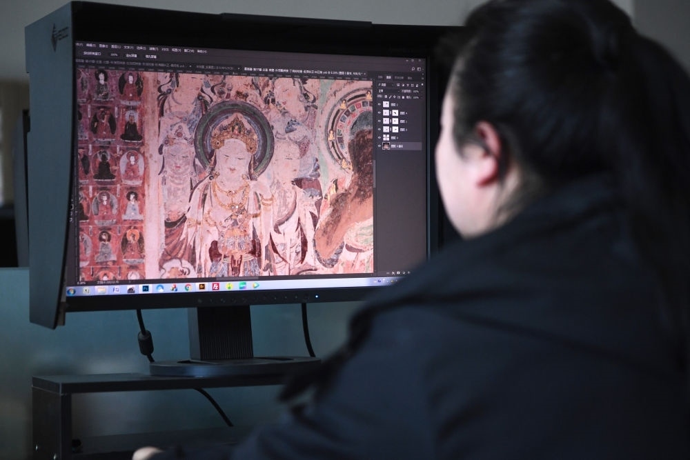 敦煌研究院文物數(shù)字化保護(hù)團(tuán)隊(duì)圖像處理人員年海麗在拼接壁畫圖像（2023年4月25日攝）。數(shù)字化探索為莫高窟的保護(hù)與傳承開辟了全新路徑，數(shù)字技術(shù)讓敦煌文物走出洞窟，跨出國(guó)門，走向“永久保存、永續(xù)利用”。新華社記者 陳斌 攝