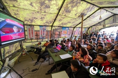 12月22日，在積石山縣大河家鎮(zhèn)大河村安置點，陸軍76集團(tuán)軍某旅搭建的“臨時學(xué)?！眱?nèi)，小朋友正在看動畫片。人民網(wǎng)記者 翁奇羽攝