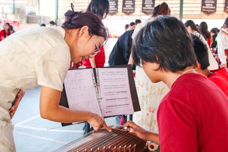 志愿者教師指導(dǎo)學(xué)生彈奏古箏?；顒又鬓k方供圖