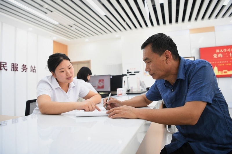 2023年5月23日，河北雄安新區(qū)容東片區(qū)南文營社區(qū)居民（右）在社區(qū)便民服務(wù)站辦理業(yè)務(wù)。