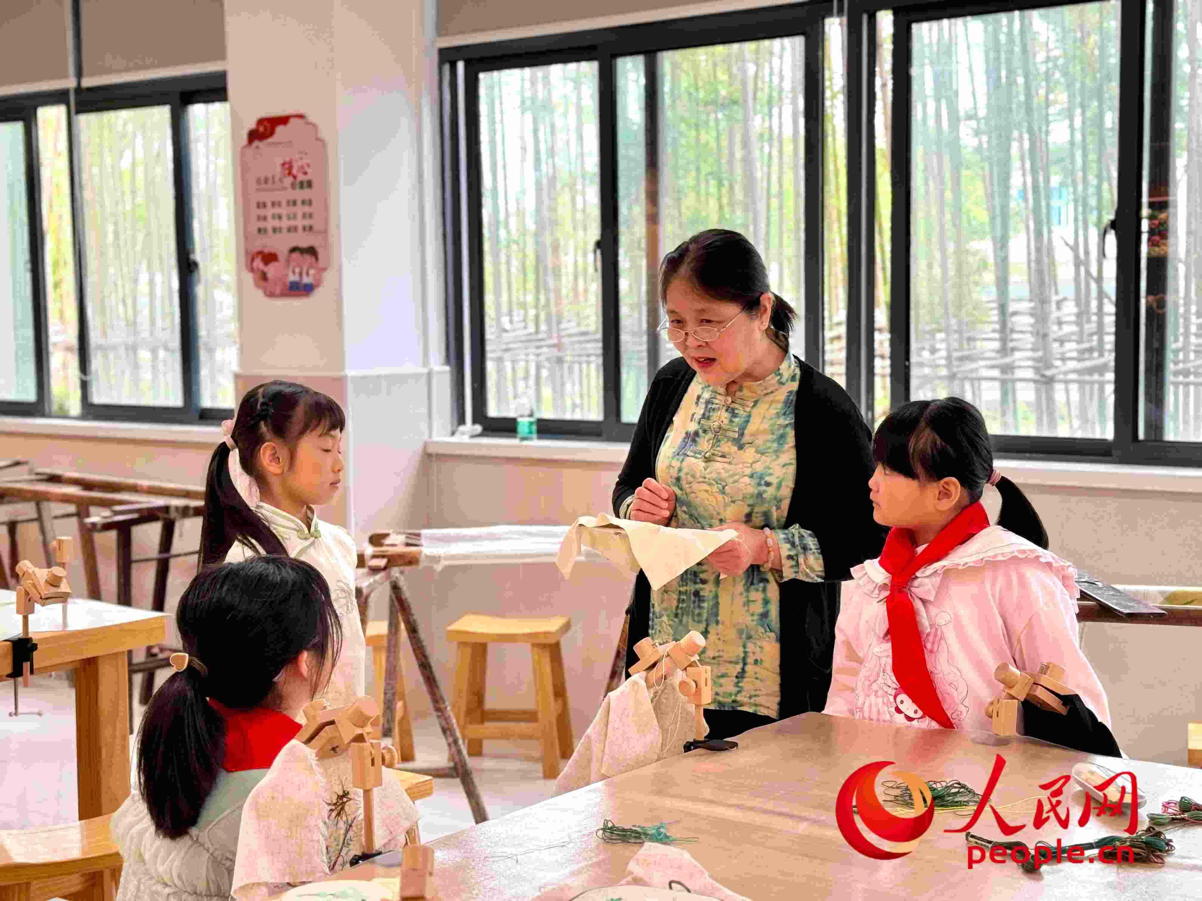 顧建珍（左三）在教孩子們刺繡知識(shí)。人民網(wǎng) 周靜圓攝