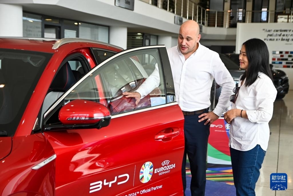 2024年5月29日，在馬耳他比爾基卡拉，馬耳他哈桑-扎米特汽車公司首席執(zhí)行官德古阿拉（左）介紹一輛比亞迪純電動(dòng)汽車。新華社發(fā)（喬納森·博格 攝）