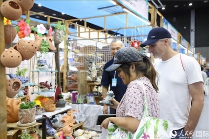 游客在蘭納博覽會特色展位上選購工藝品。人民網(wǎng)記者楊一攝