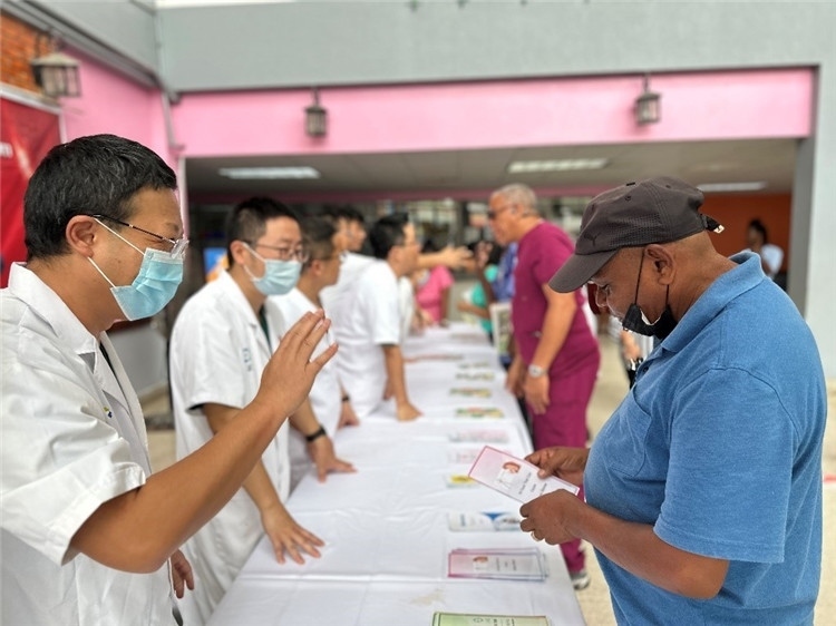 援圭醫(yī)療隊(duì)隊(duì)員們?cè)趩?dòng)儀式上為當(dāng)?shù)孛癖姺职l(fā)宣傳手冊(cè)。中國(guó)援助圭亞那醫(yī)療隊(duì)供圖