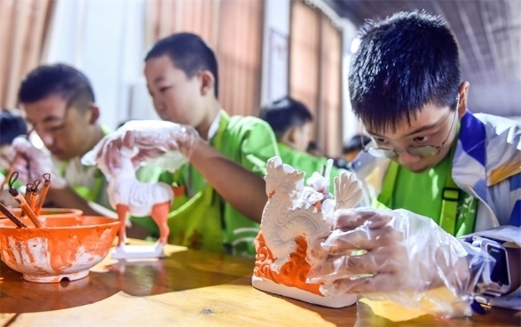 小朋友們在洛陽市孟津區(qū)朝陽鎮(zhèn)南石山村體驗唐三彩素胎施釉技藝。圖片來源：視覺中國
