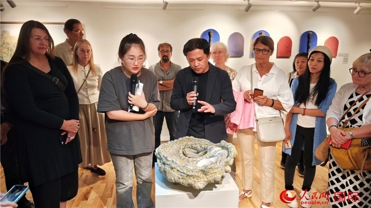參展人、景德鎮(zhèn)陶瓷大學(xué)設(shè)計(jì)藝術(shù)學(xué)院副院長(zhǎng)余劍峰（中）向來(lái)賓介紹參展作品。人民網(wǎng)記者 殷淼攝