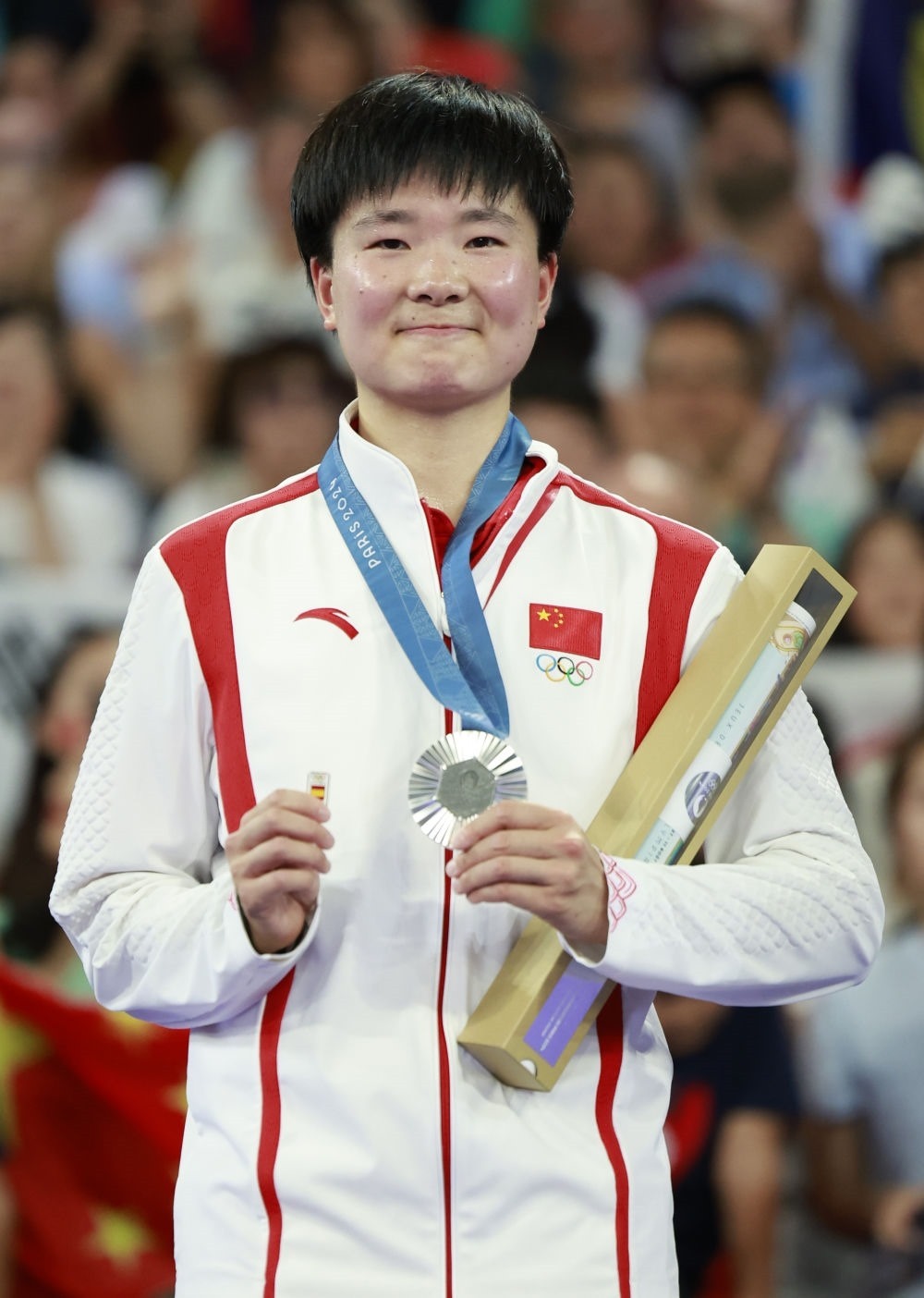 巴黎奧運(yùn)會(huì)羽毛球女子單打亞軍、中國(guó)選手何冰嬌在頒獎(jiǎng)儀式上一手握著銀牌，一手握著西班牙奧委會(huì)徽章（2024年8月5日攝）。新華社記者 任正來 攝