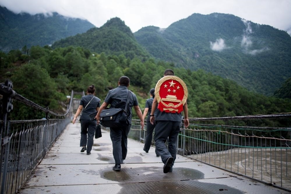 云南省怒江傈僳族自治州貢山縣人民法院法官鄧興背著國徽與同事們跨過怒江（2019年8月30日攝）。怒江高山峽谷眾多，交通不便，為方便群眾、更好地開展法律服務，背著國徽攀高山、過索橋、躲落石、鉆老林……成為鄧興法官的工作常態(tài)。新華社記者 江文耀 攝