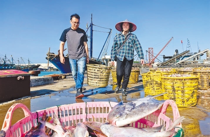 許小斌（左）和漁民一起搬運(yùn)海鮮。本報(bào)記者 付 文攝