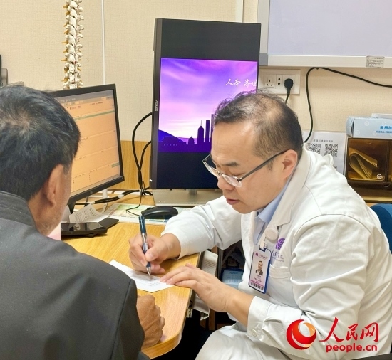 路桂軍接診時(shí)為患者寫下用藥提示。人民網(wǎng)記者 金慧慧攝