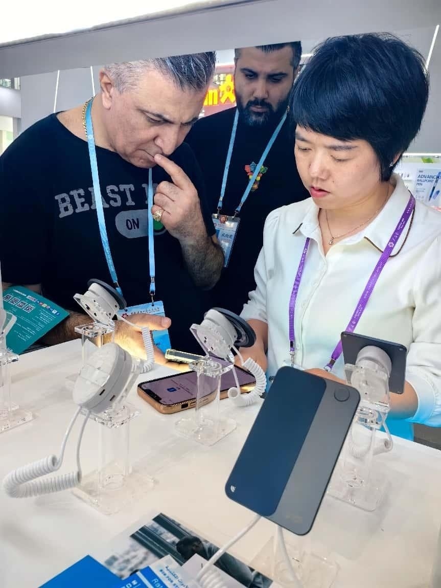 展臺(tái)工作人員向外商展示“AI TOP翻譯終端”。圖片來(lái)源：受訪者提供
